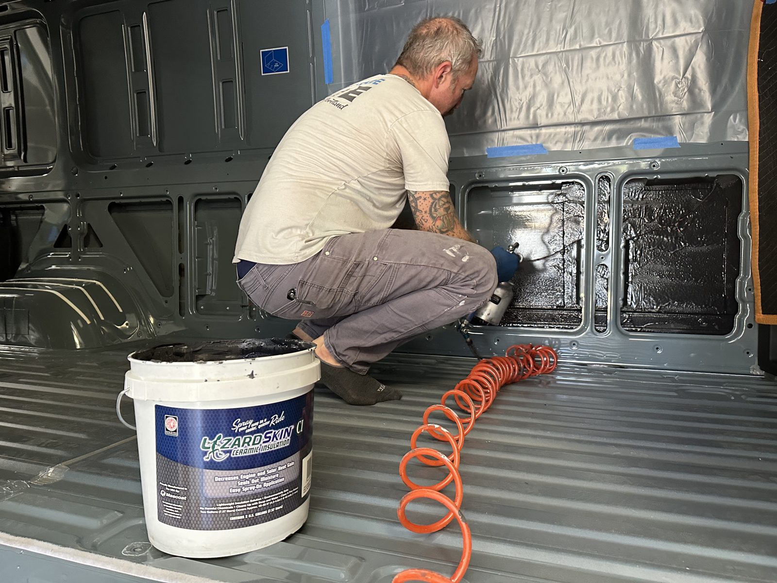 Spraying Lizard Skin ceramic insulation onto the van's bare steel
